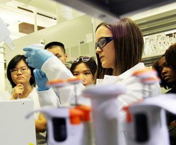 Professor Monroe and students examine a sample in a laboratory.