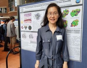 A student stands in front of a research poster