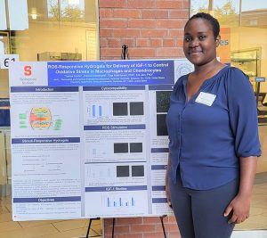A student stands in front of a scientific poster